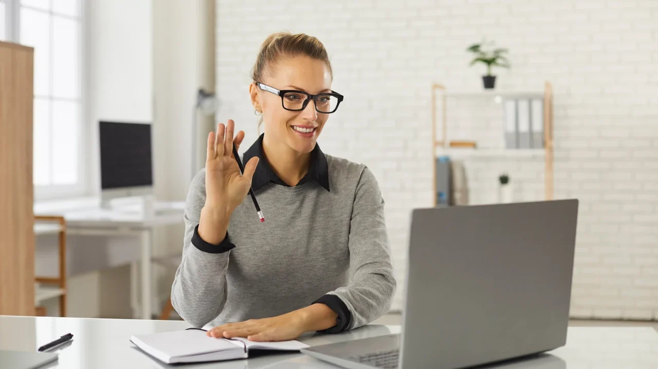 Professional greeting someone on a laptop video call.