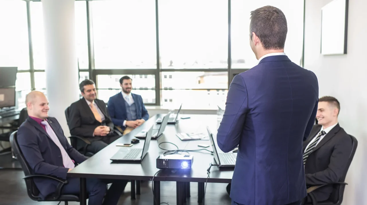 Professional presenting to colleagues in a meeting room.