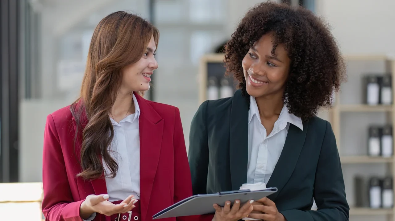Two professionals smiling while reviewing a tablet.