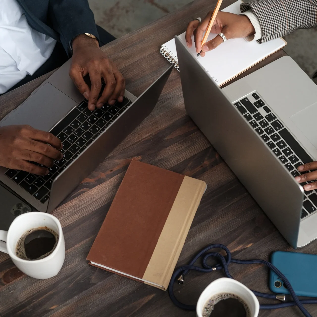 Colleagues working with laptops around a desk.