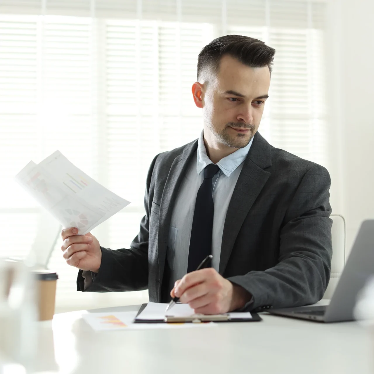 Professional reviewing a printed document at a desk.