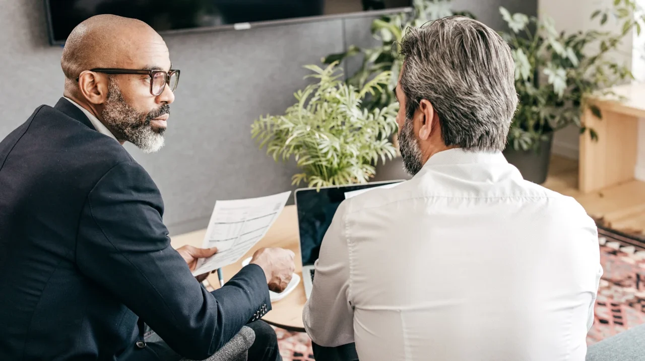 Two colleagues discussing a printed document.