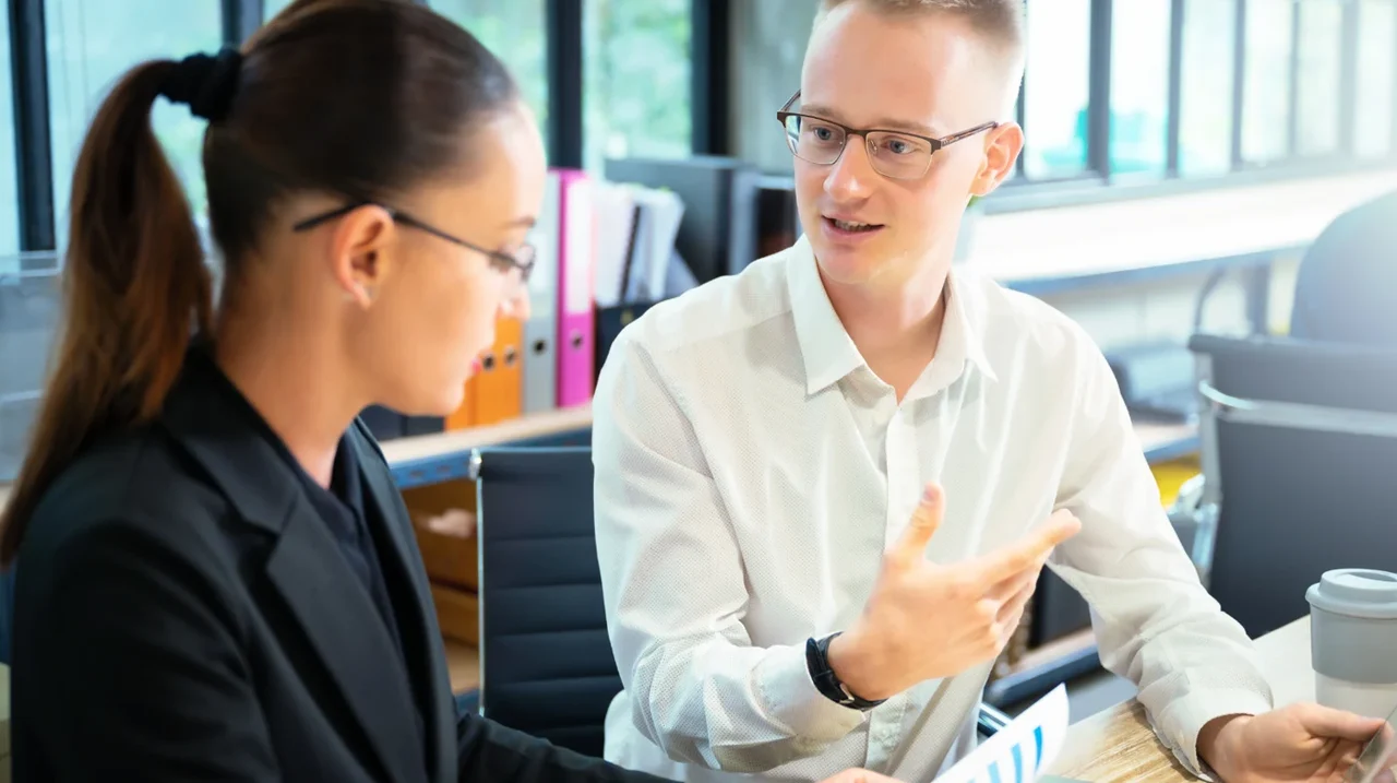 Two colleagues talking at a desk.