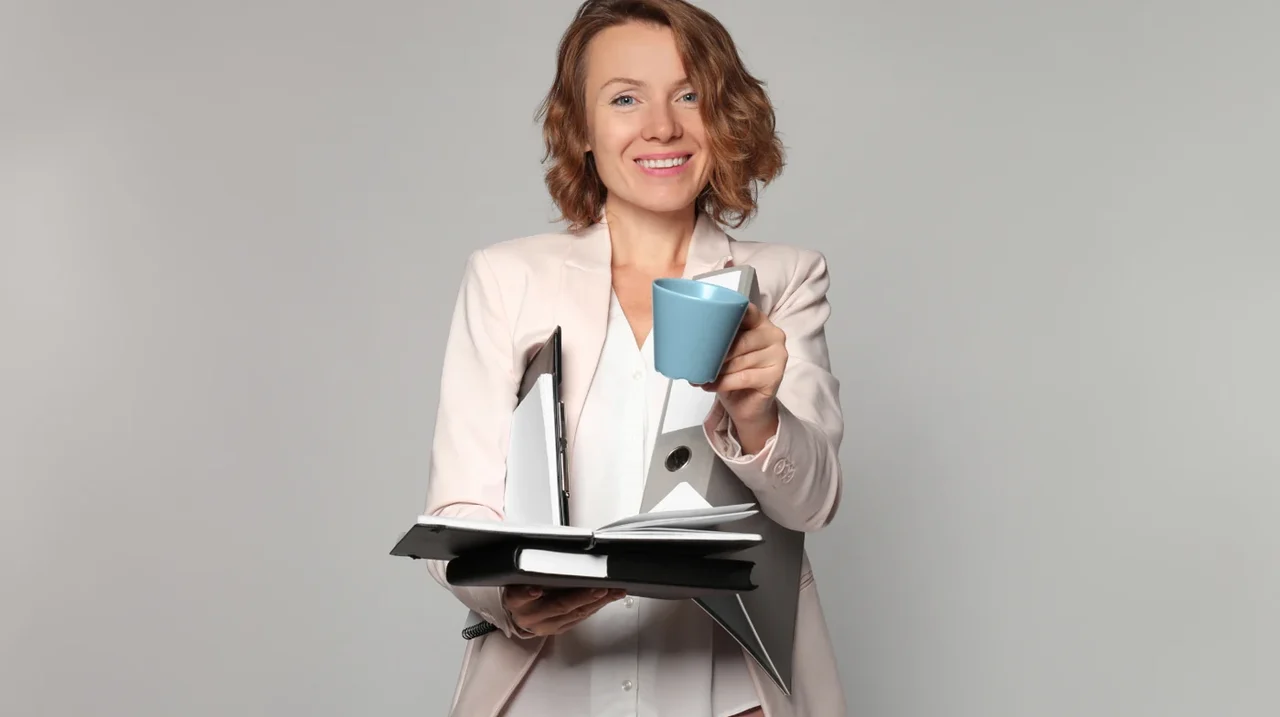Professional holding a notebook and a cup.