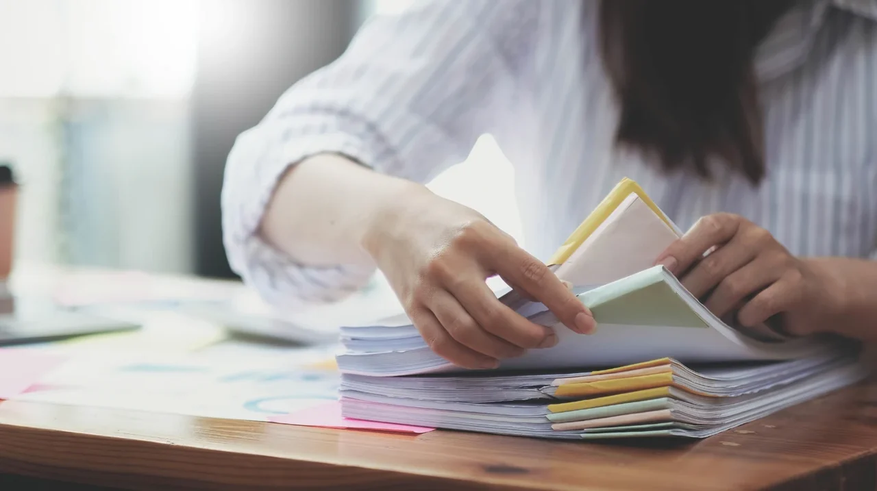 Hands arranging colored notes and papers on a desk.