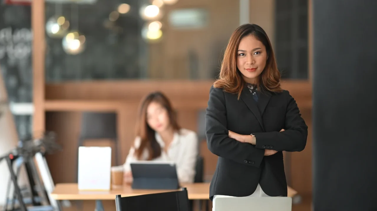 Professional standing confidently in a shared workspace.