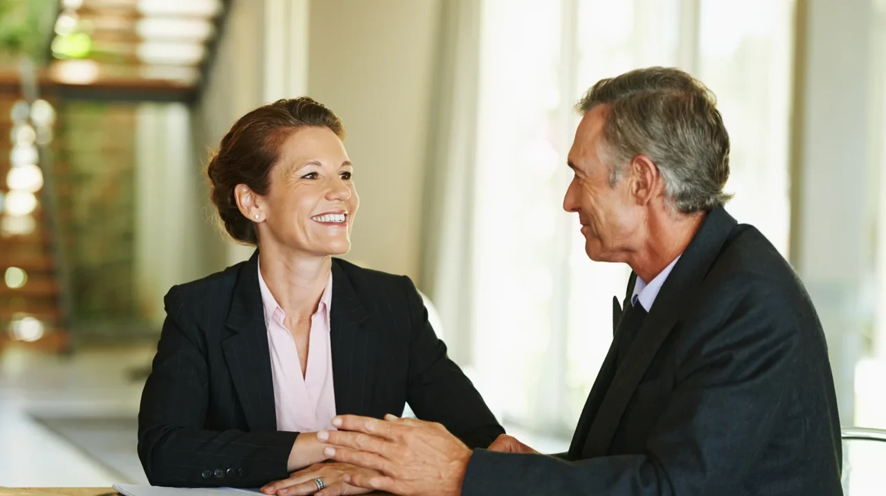 Two professionals shaking hands and smiling.