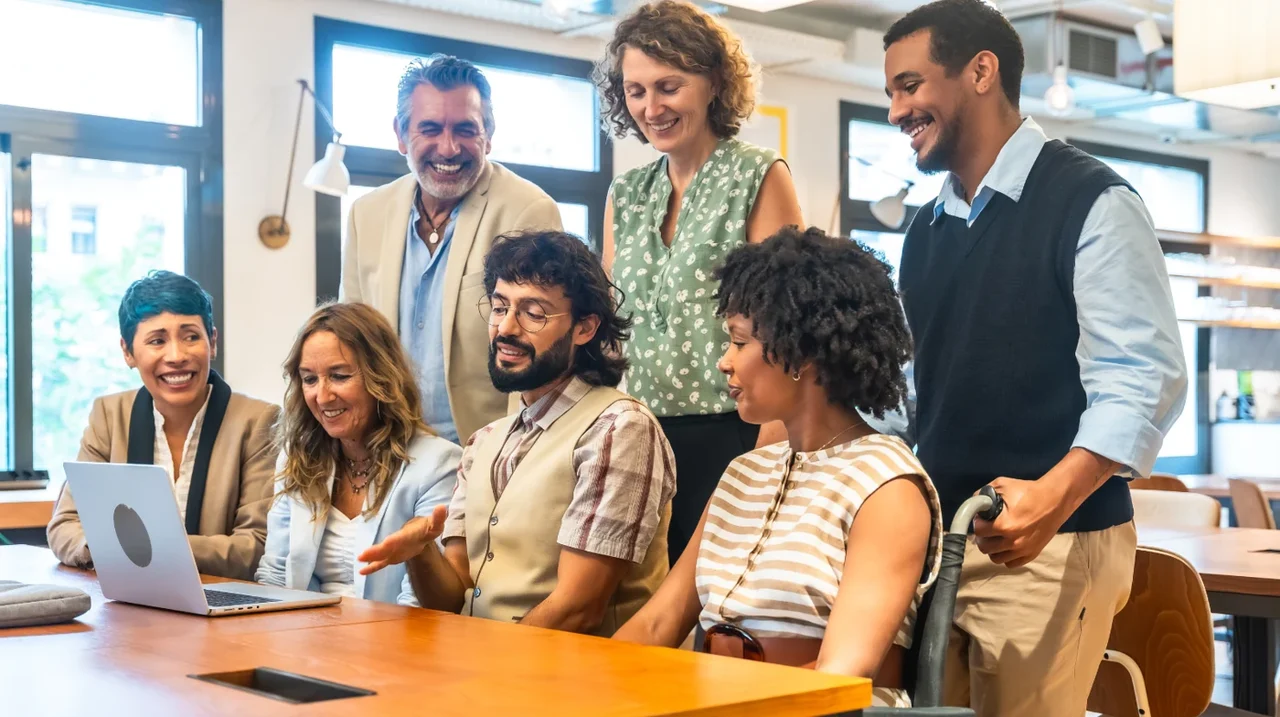 A diverse team collaborating around a computer.