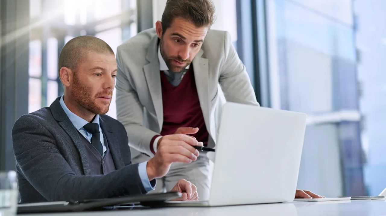 Two colleagues discussing work on a laptop.