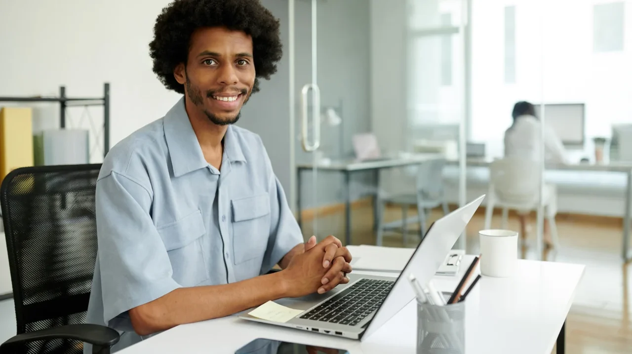 Professional smiling while working on a laptop.