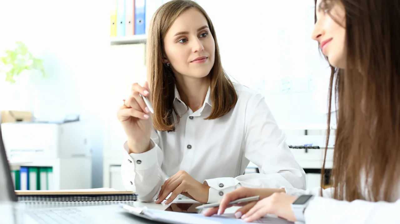 Two professionals discussing a document in a bright workplace.
