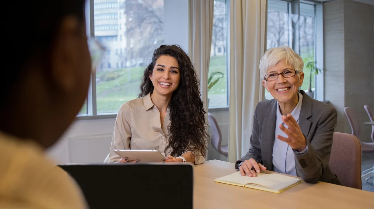 Two professionals smiling during a conversation.