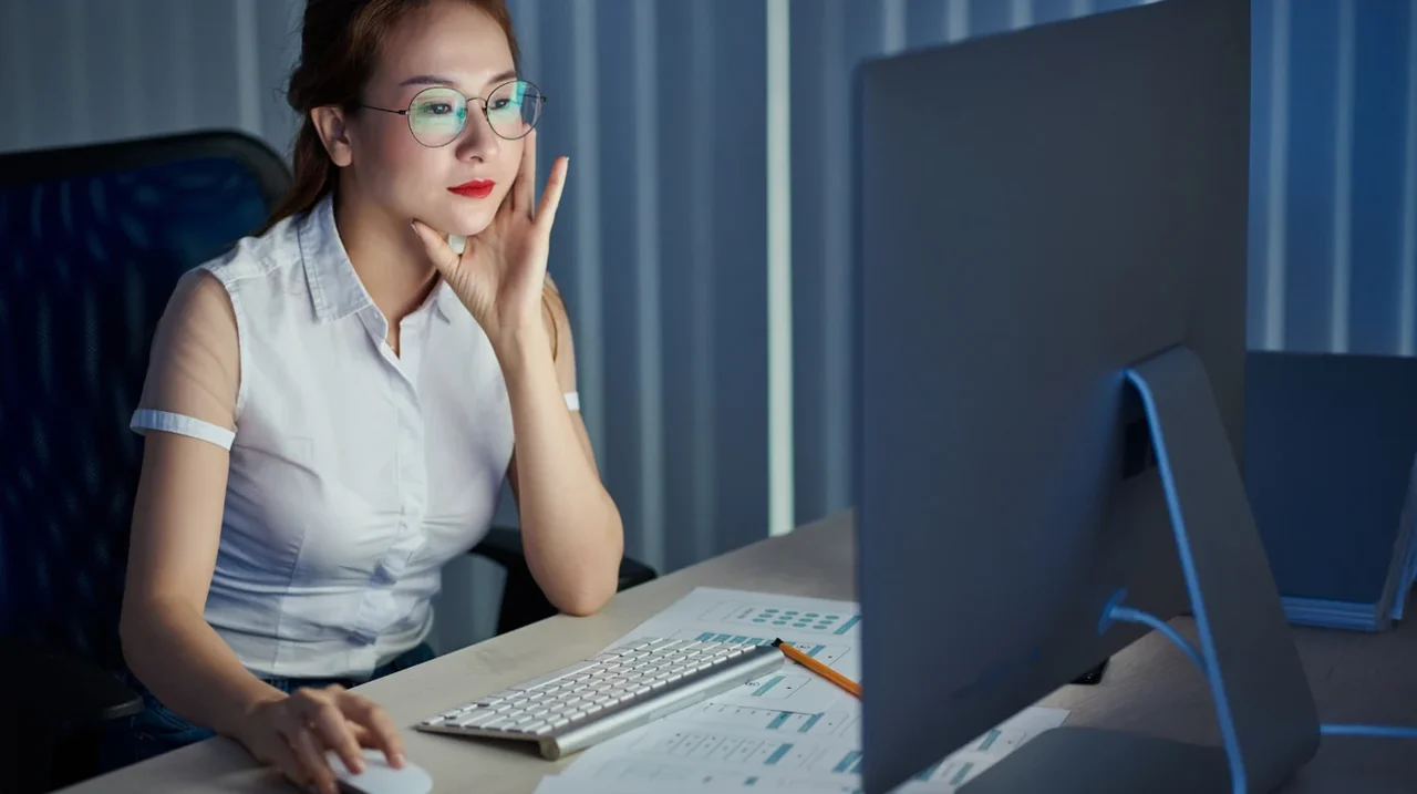 Professional concentrating at a computer in a quiet evening workspace.
