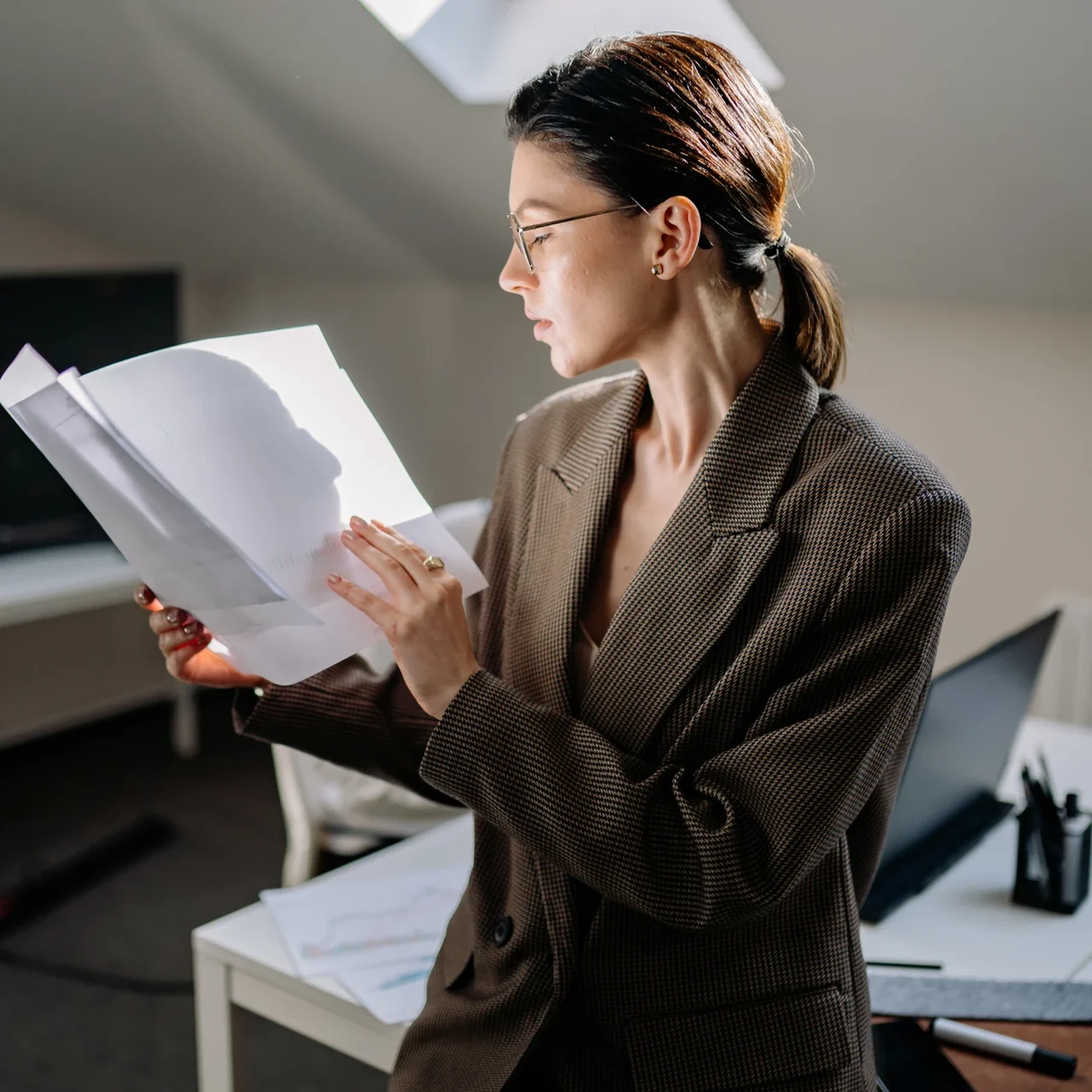 Professional reviewing printed documents in a sunlit workspace.