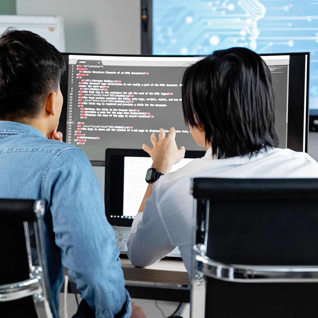 Colleagues examining code together on a computer screen.