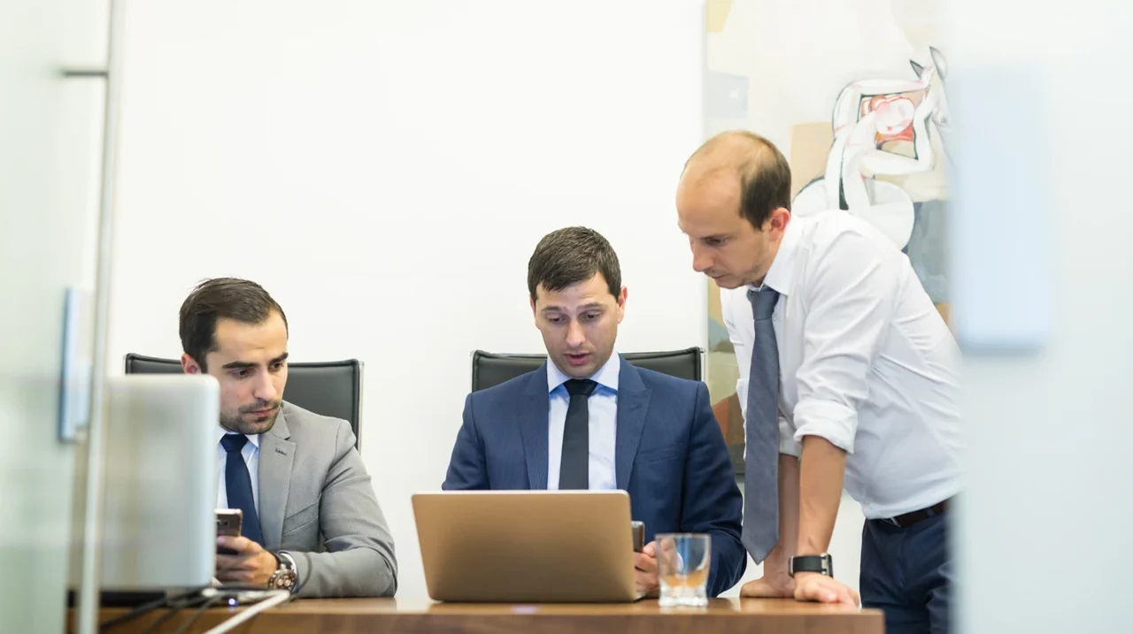 Three colleagues looking at a laptop.
