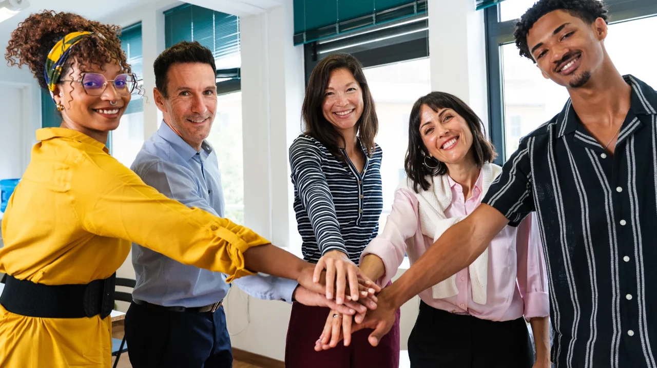 Colleagues joining hands in a team celebration.