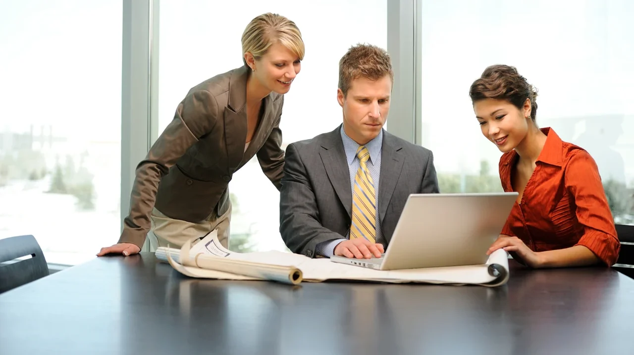 Three colleagues reviewing information on a laptop.