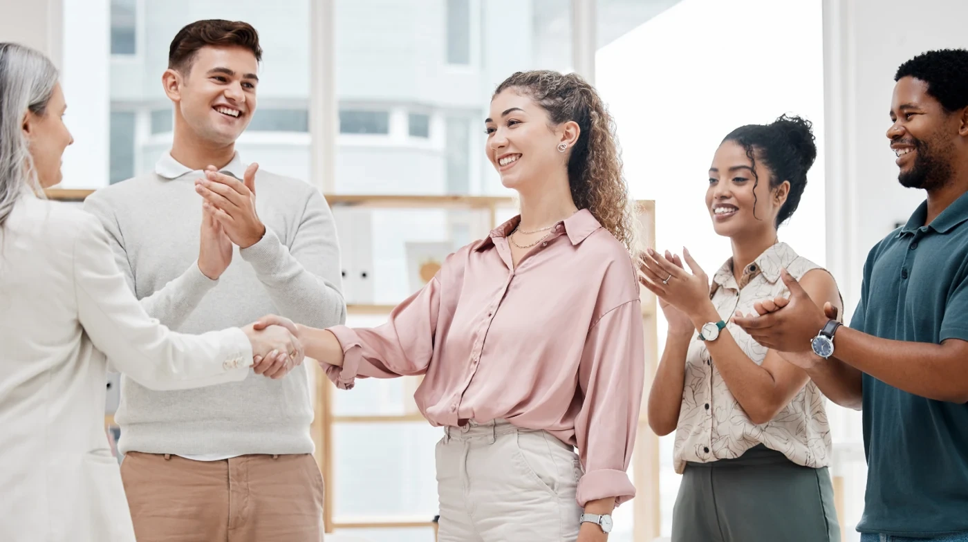 Colleagues applauding as a professional receives congratulations.