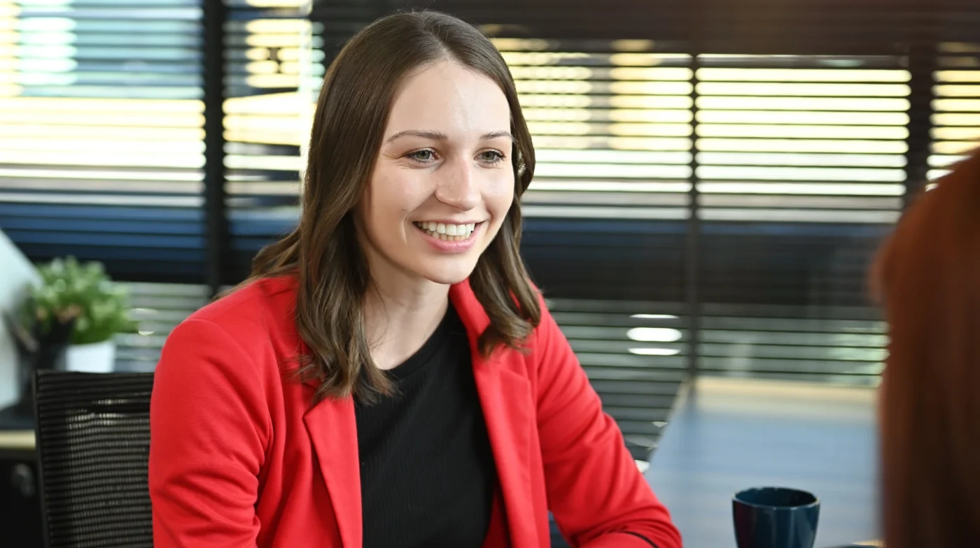 Smiling professional in a red jacket during a conversation.